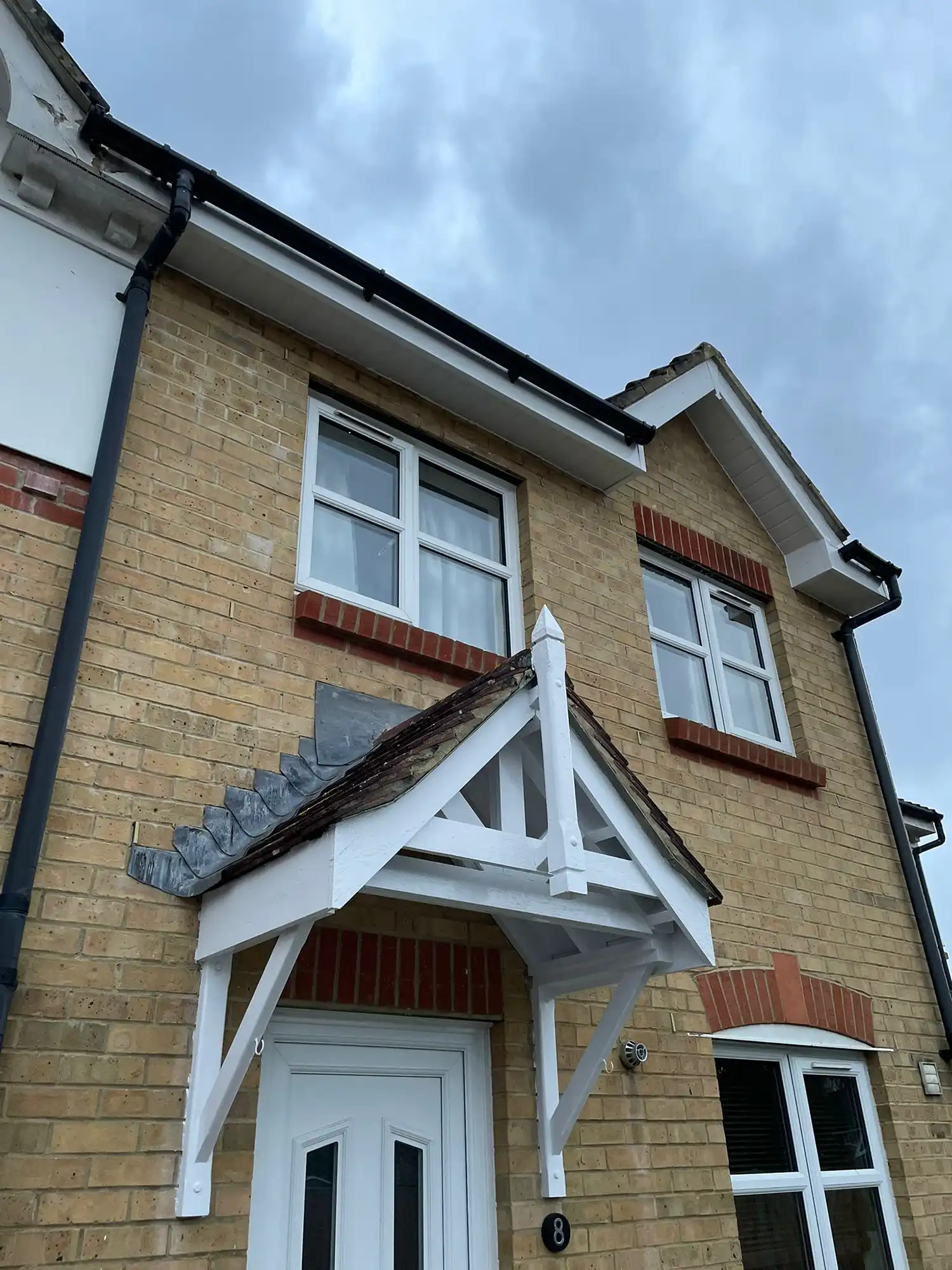 A house with a white door and a brown brick wall.