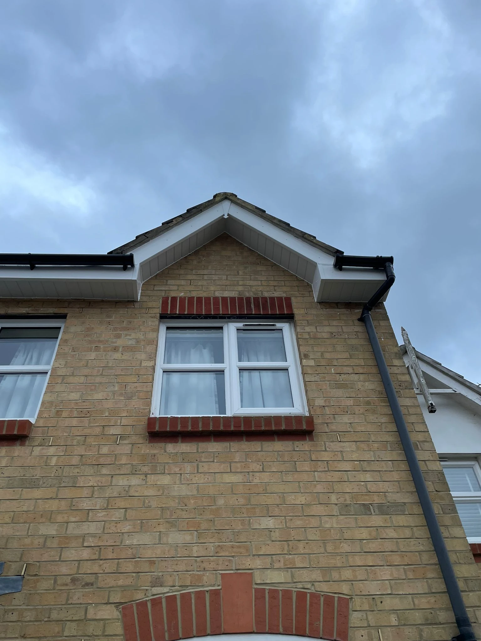 A brick building with two windows and a sky background.