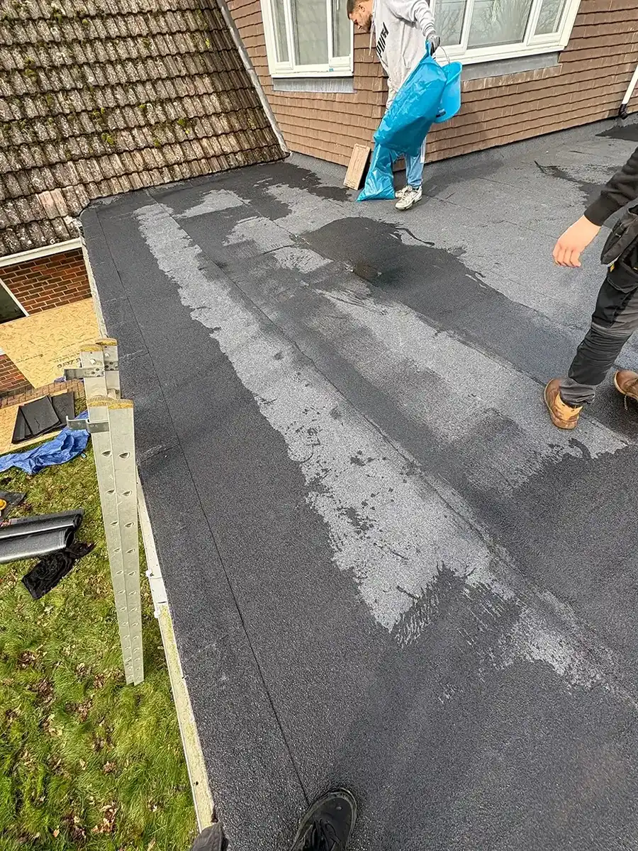 Two men standing on a new torch layed flat rof.
